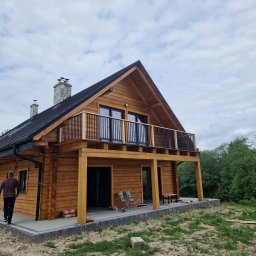 LOFT WELDING Krystian Kudela - Drewniany dom z balkonem z czarną, metalową balustradą, widok z zewnątrz, częściowo zagospodarowany teren.