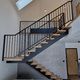 LOFT WELDING Krystian Kudela - Nowoczesne schody z drewnianymi stopniami i czarną metalową balustradą w jasnym wnętrzu z oknem dachowym. Sofa zabezpieczona folią ochronną.