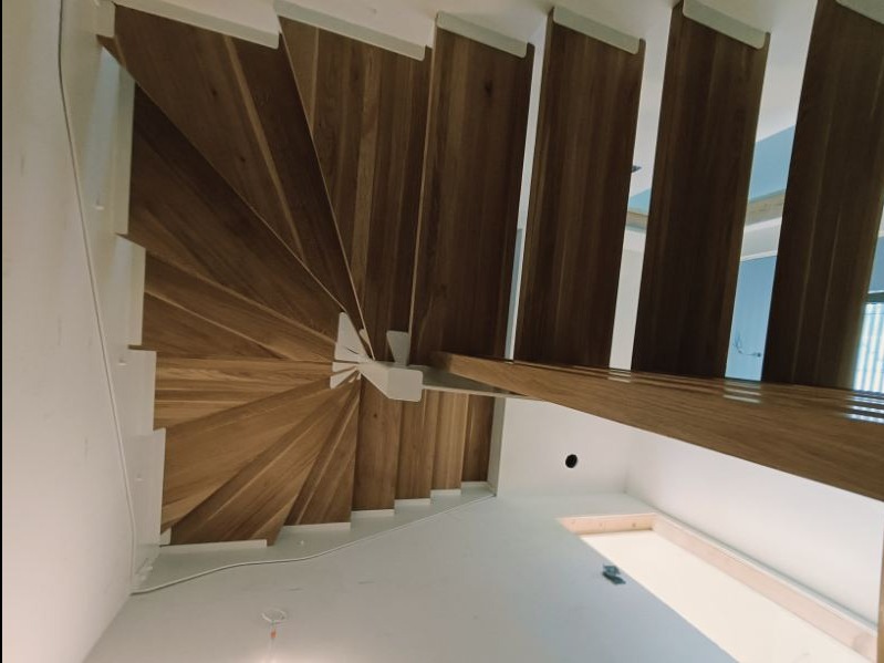 Spiralne schody drewniane z białymi elementami konstrukcyjnymi, widok z dołu, Wyźrał.