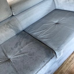 Mw Błysk - Szara, narożna kanapa z widocznymi plamami przed czyszczeniem, z fragmentem odkurzacza piorącego w rogu.