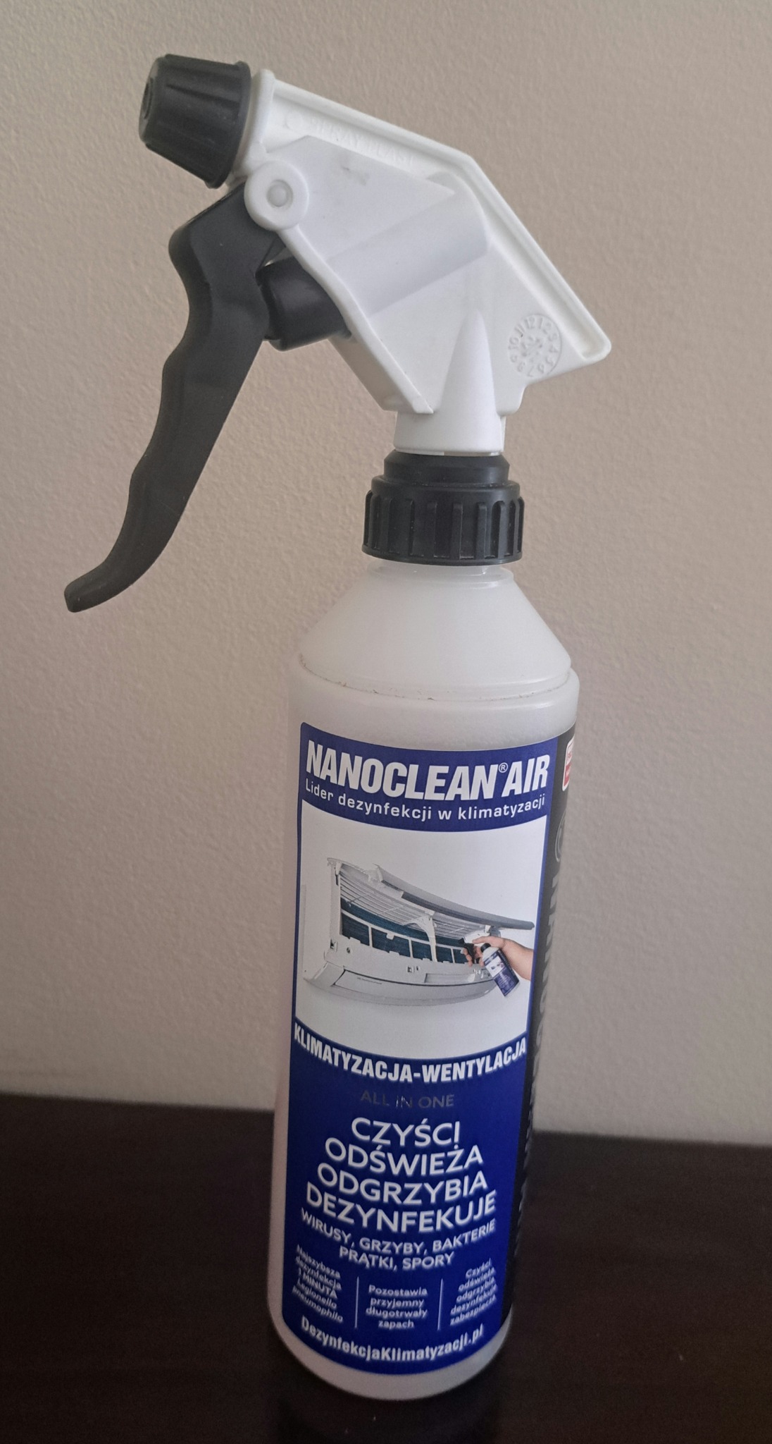 Butelka środka dezynfekującego Nanoclean Air do klimatyzacji z rozpylaczem, etykieta informuje o czyszczeniu, odświeżaniu, odgrzybianiu i dezynfekcji klimatyzacji i wentylacji.