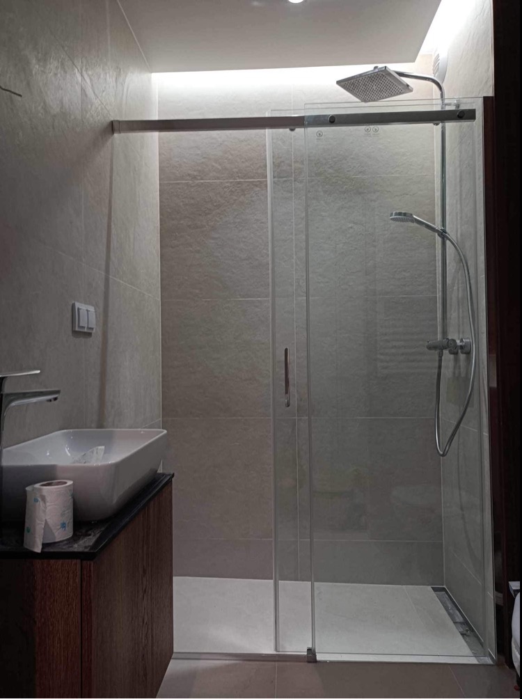 Nowoczesna łazienka z kabiną prysznicową typu walk-in, umywalką nablatową na drewnianej szafce i szarą płytką na ścianach.