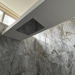 Łukasz - Nowoczesna łazienka z deszczownicą w suficie i ścianami wyłożonymi płytkami imitującymi marmur w odcieniach szarości, widok z dołu.