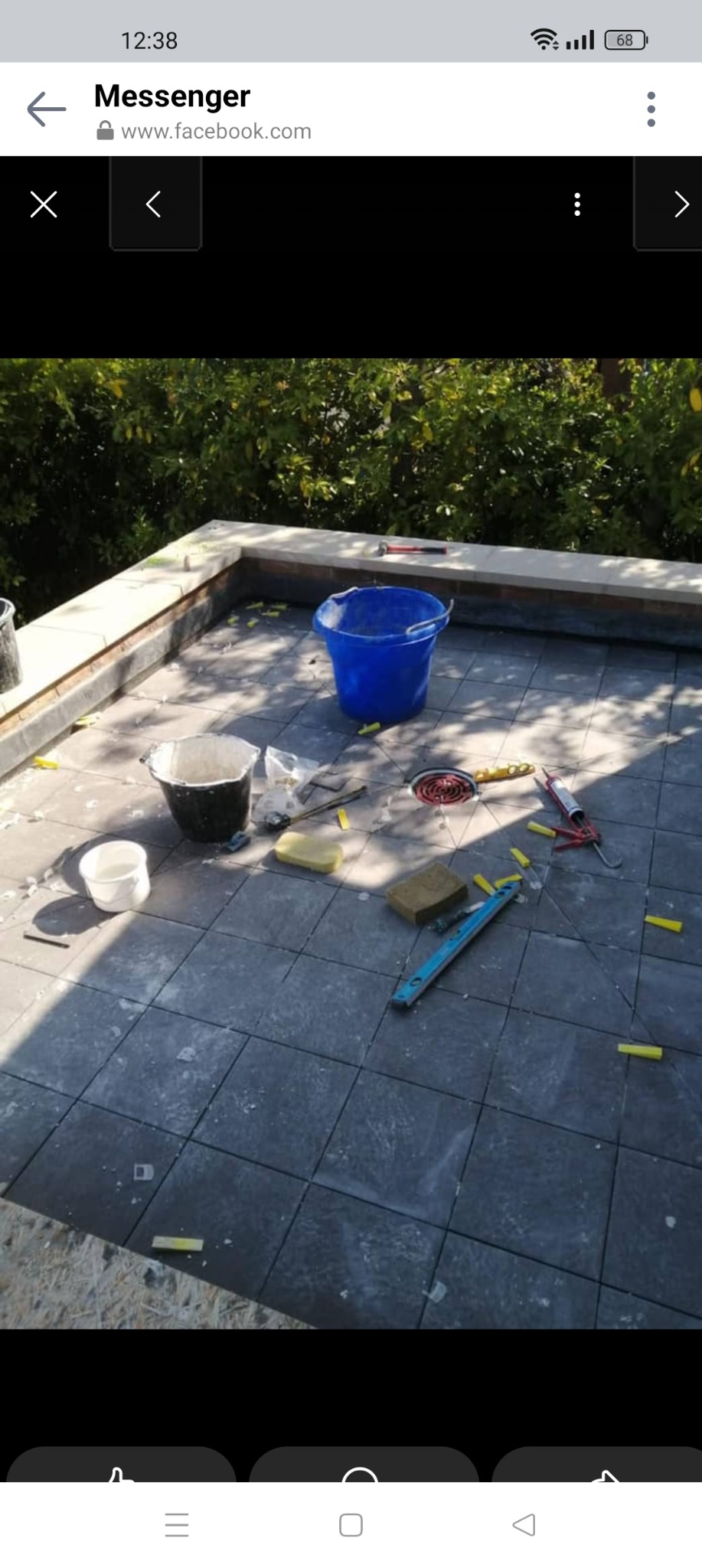 Kładzenie ciemnoszarej terakoty na zewnątrz, widoczne narzędzia glazurnicze, poziomica, wiaderka, gąbki, krzyżyki dystansowe i odpływ liniowy.