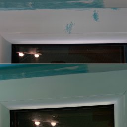 Umyć szybkę - Detale ramy okiennej z widocznymi pozostałościami po taśmie malarskiej i śladami farby na ścianie powyżej, ukazujące etap przygotowania do malowania lub niedokładne usunięcie zabezpieczeń.