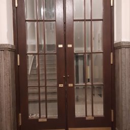 AG-MAR - Klasyczne, dwuskrzydłowe drzwi drewniane z przeszkleniami, widoczne z bliska w Morawicy. Za drzwiami widoczne schody.