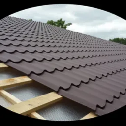 Widok na częściowo pokryty dach z brązowej blachodachówki, widoczna konstrukcja drewniana i warstwa izolacyjna, na tle pochmurnego nieba.