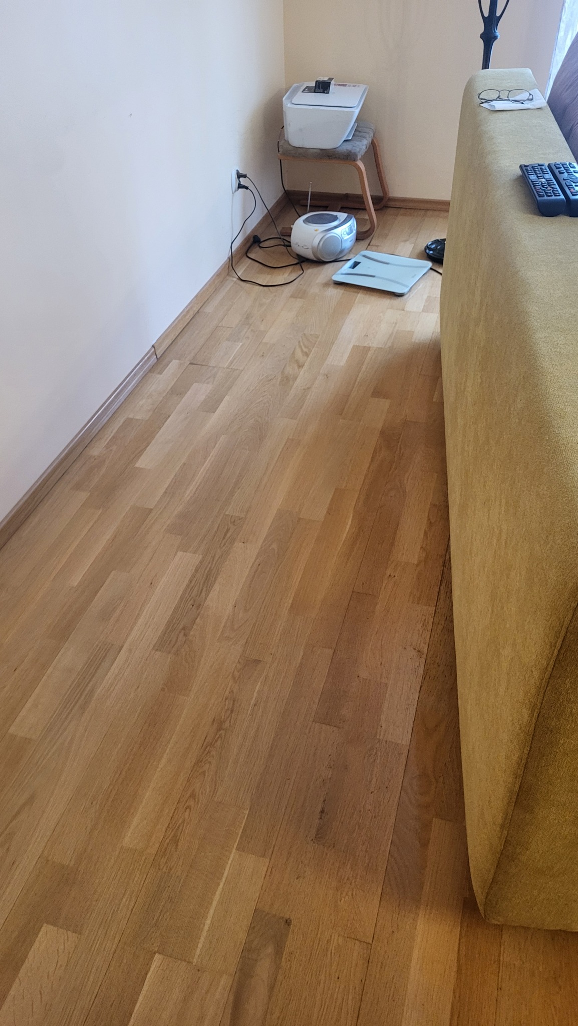 Parkiet po cyklinowaniu i lakierowaniu, widoczne meble i sprzęty. Podłoga z jasnego drewna, gładka powierzchnia, brak zabrudzeń. Ujęcie z perspektywy podłogi.