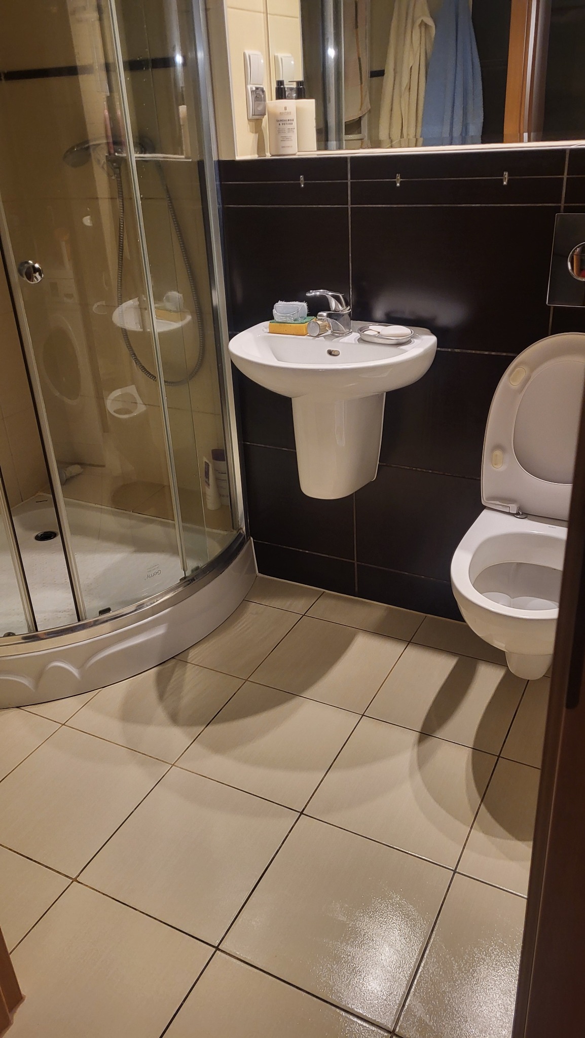 Umywalka, toaleta i kabina prysznicowa w łazience po sprzątaniu. Widoczne czyste płytki podłogowe i brak zacieków na kabinie.