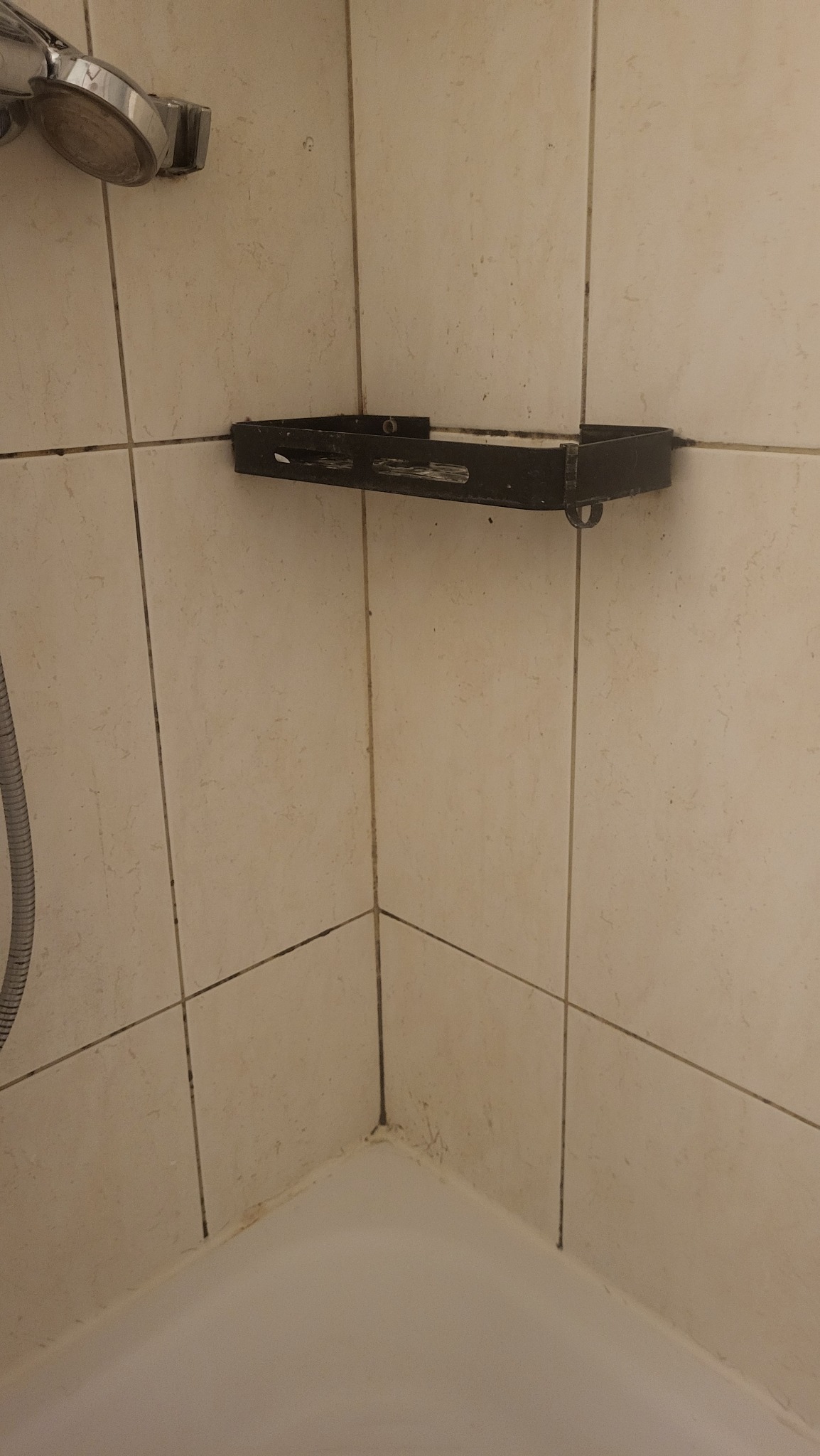 Zaniedbana kabina prysznicowa z widocznymi zabrudzeniami na fugach i półce. Widoczny osad i brak czystości. Potrzeba gruntownego czyszczenia.