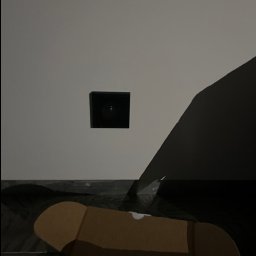 ELEKTRO-CIERBIKOWSKI KRYSTIAN CIERBIKOWSKI - Kamera alarmowa w czarnej obudowie zamontowana na białej ścianie, z widocznym kartonowym pudełkiem na pierwszym planie i fragmentem czarnego przedmiotu po prawej stronie.