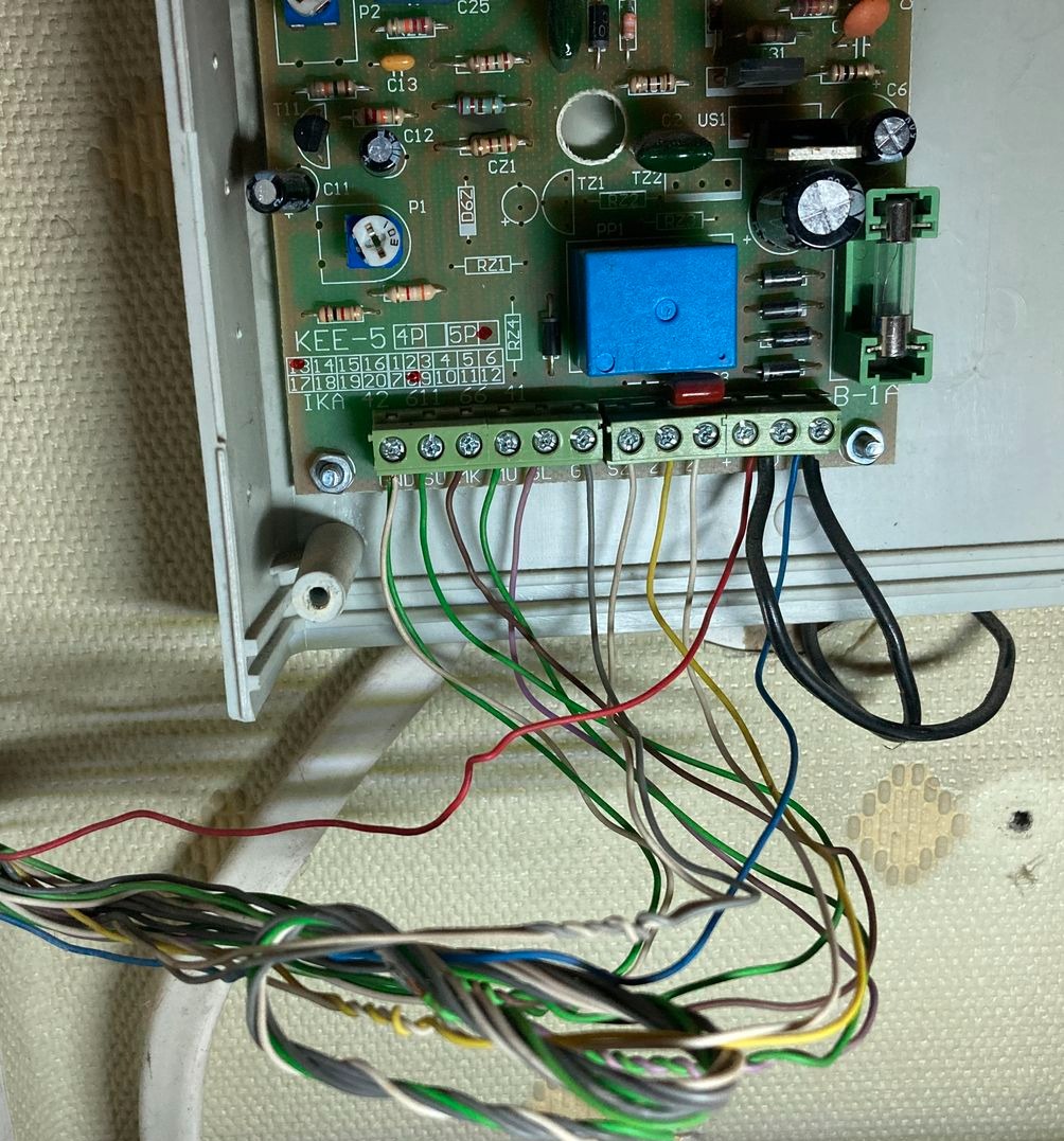 Podłączenie przewodów do płyty sterującej systemu alarmowego z widocznymi elementami elektronicznymi i złączkami śrubowymi.