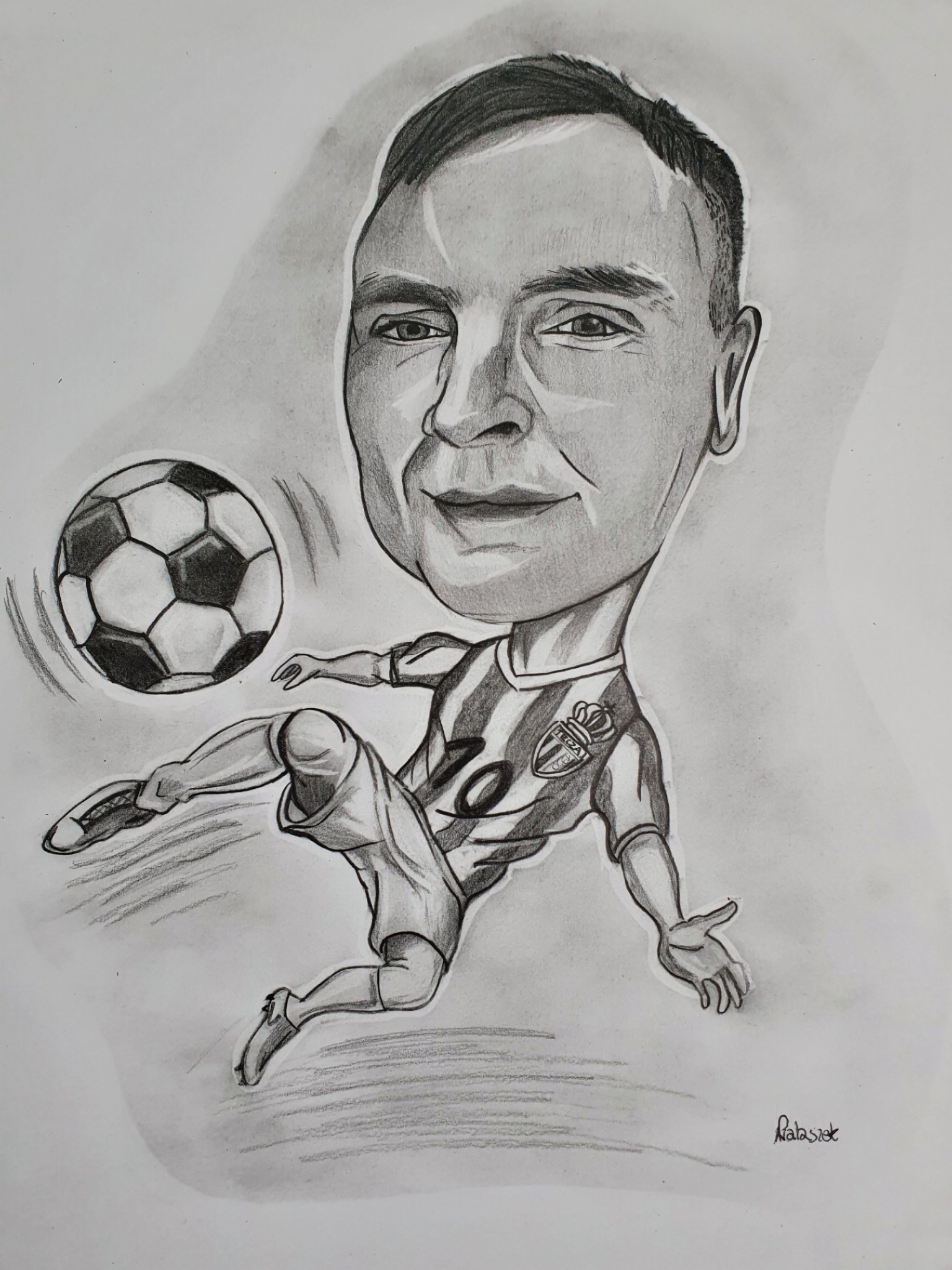 Czarno-biały rysunek ołówkiem przedstawiający karykaturę piłkarza kopiącego piłkę, z widocznym logo klubu 'TEGZA' na koszulce.