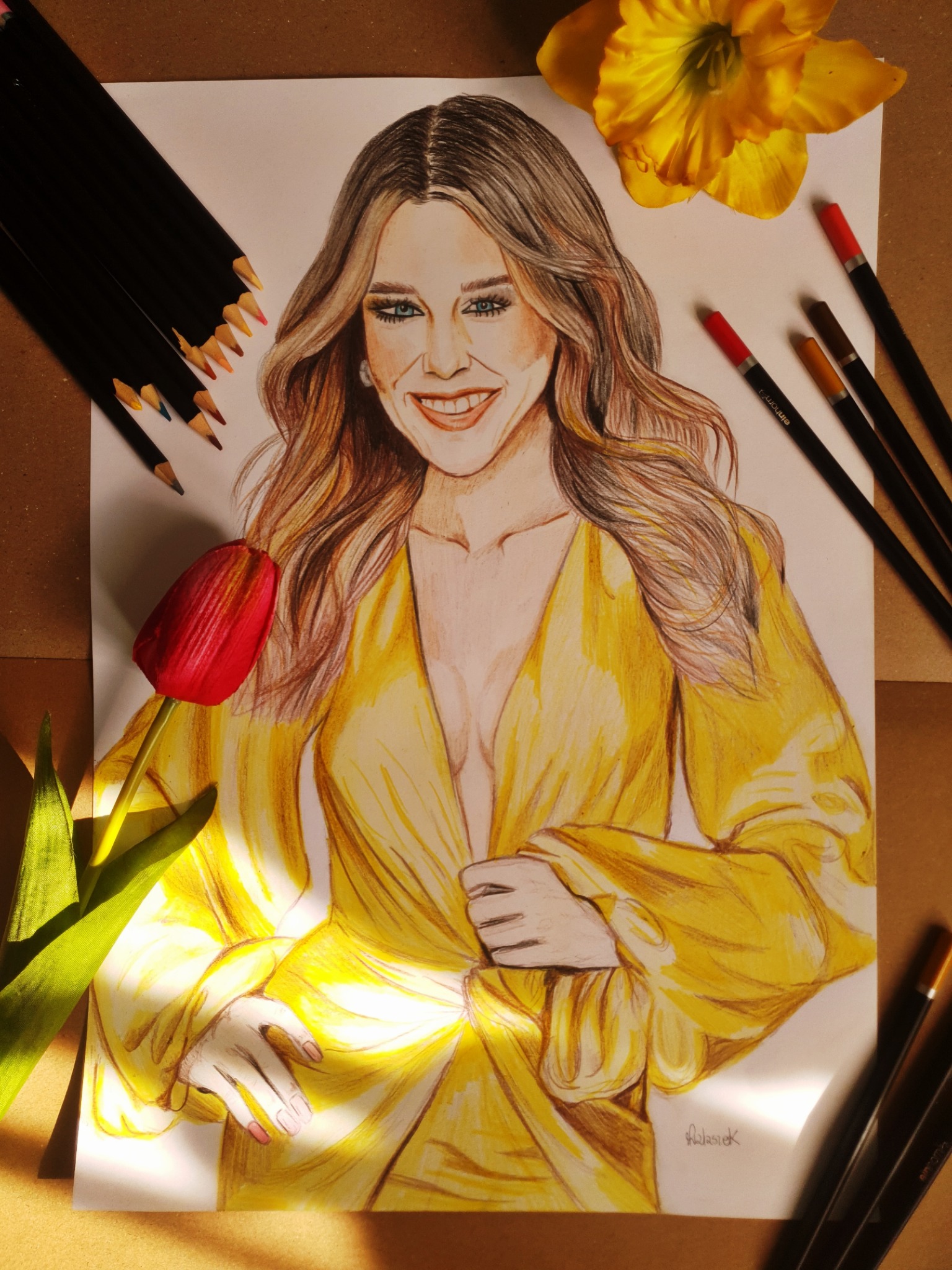 Portret kobiety w żółtej sukni narysowany kredkami, otoczony tulipanem, narcyzem i zestawem kredek na brązowym tle.