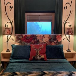 Zubek Frez CNC - Sypialnia z łóżkiem w stylu rustykalnym, drewniane panele z wyciętymi wzorami roślinnymi po bokach, kwiatowy zagłówek, zielone poduszki i narzuta, czerwona poduszka z wizerunkiem jelenia w mundurze...