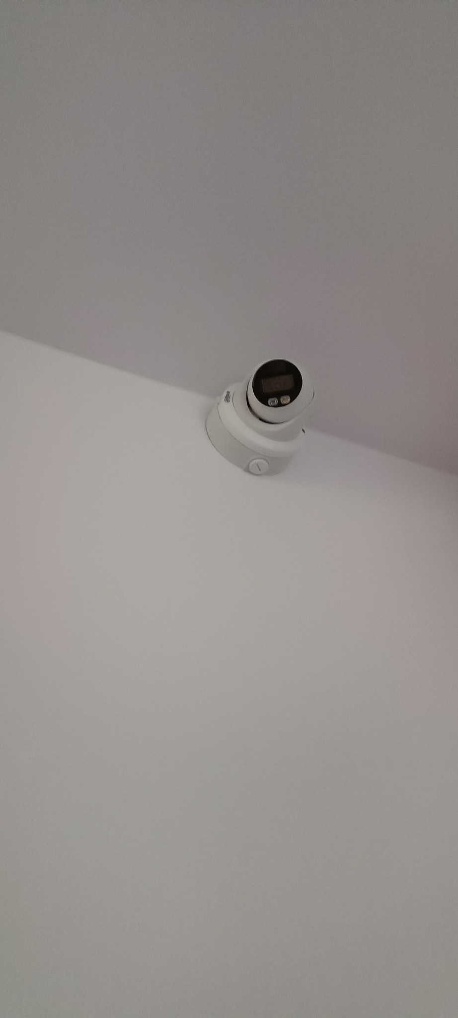 Kamera kopułkowa monitoringu, biała, zamontowana na suficie, widoczny wyświetlacz i przyciski, ujęcie z dołu.