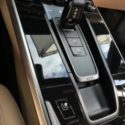 Wnętrze samochodu: detale konsoli środkowej z dźwignią zmiany biegów w pozycji 'N', przyciski regulacji temperatury i podgrzewania foteli, wykończenie z czarnego lakieru fortepianowego odbijające...