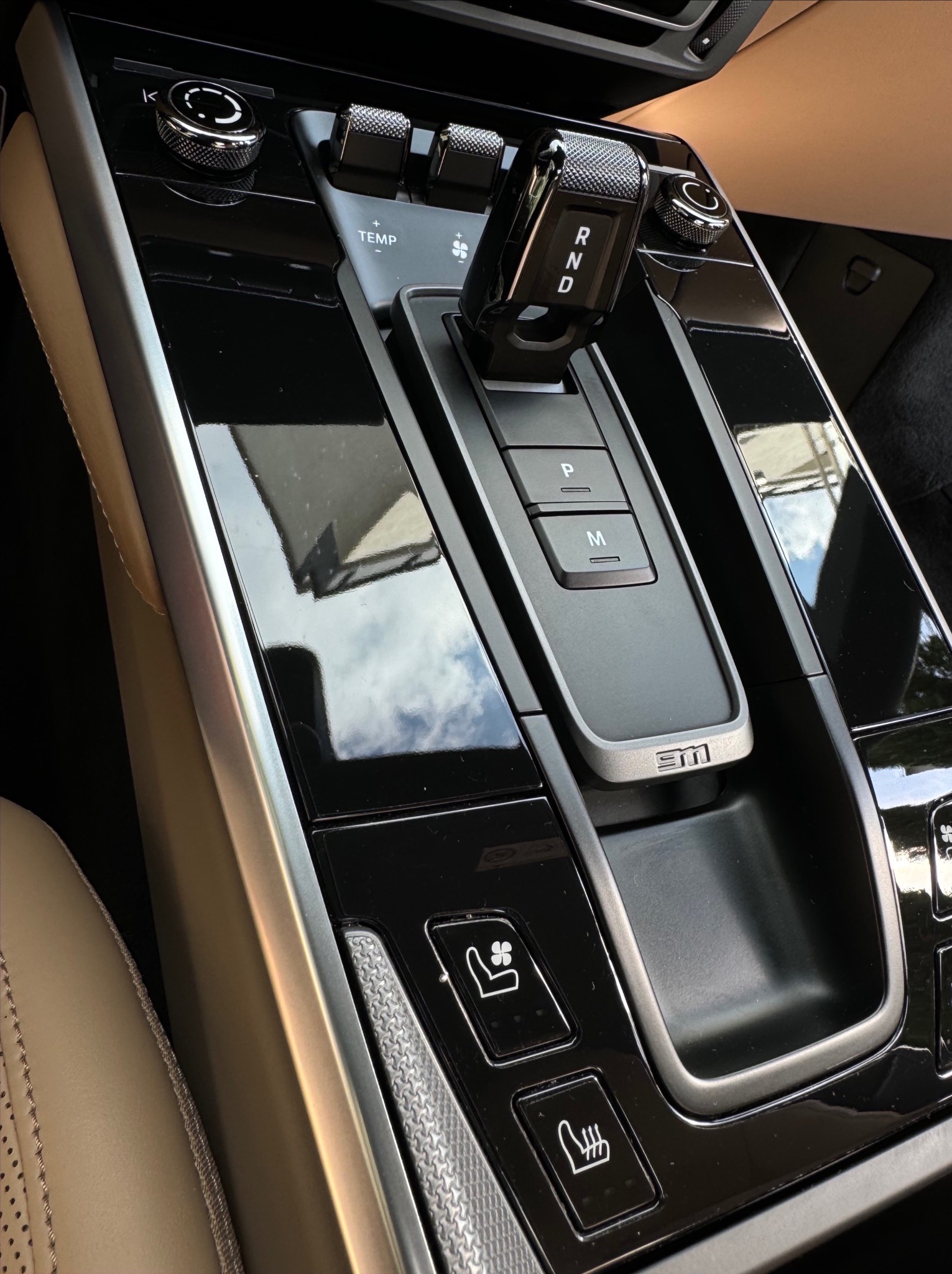 Wnętrze samochodu: detale konsoli środkowej z dźwignią zmiany biegów w pozycji 'N', przyciski regulacji temperatury i podgrzewania foteli, wykończenie z czarnego lakieru fortepianowego odbijające...