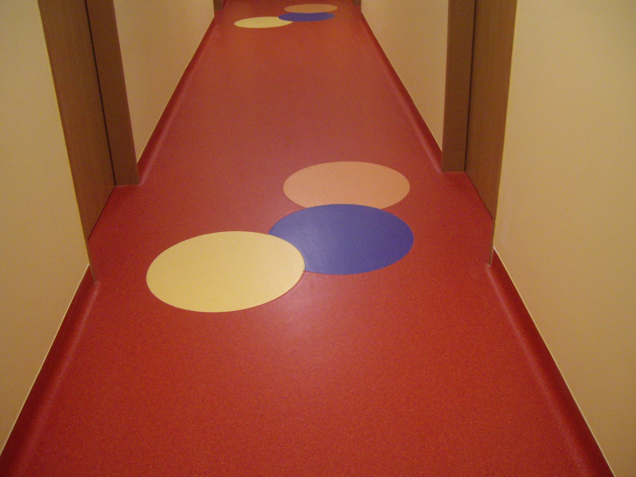 Czerwona wykładzina podłogowa z kolorowymi okręgami w korytarzu, widok z perspektywy podłogi