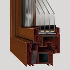 Przekrój brązowego okna PCV DECCO 83, ukazujący wielokomorową budowę profilu i trzyszybowy pakiet szkła.