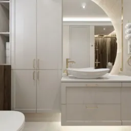 Elegancka łazienka w odcieniach beżu i bieli z drewnianymi akcentami, owalna umywalka nablatowa z złotą armaturą, duże lustro z dekoracyjnym oświetleniem, grzejnik drabinkowy i rolety w oknie.