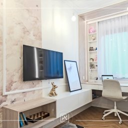 Piotr Krawczyk Studio Projektowe - Nowoczesny pokój dzienny z miejscem do pracy: telewizor na ścianie z tapetą w pastelowe wzory, biurko z laptopem przy oknie z białymi zasłonami, złota figurka królika, drewniany parkiet w jodełkę.