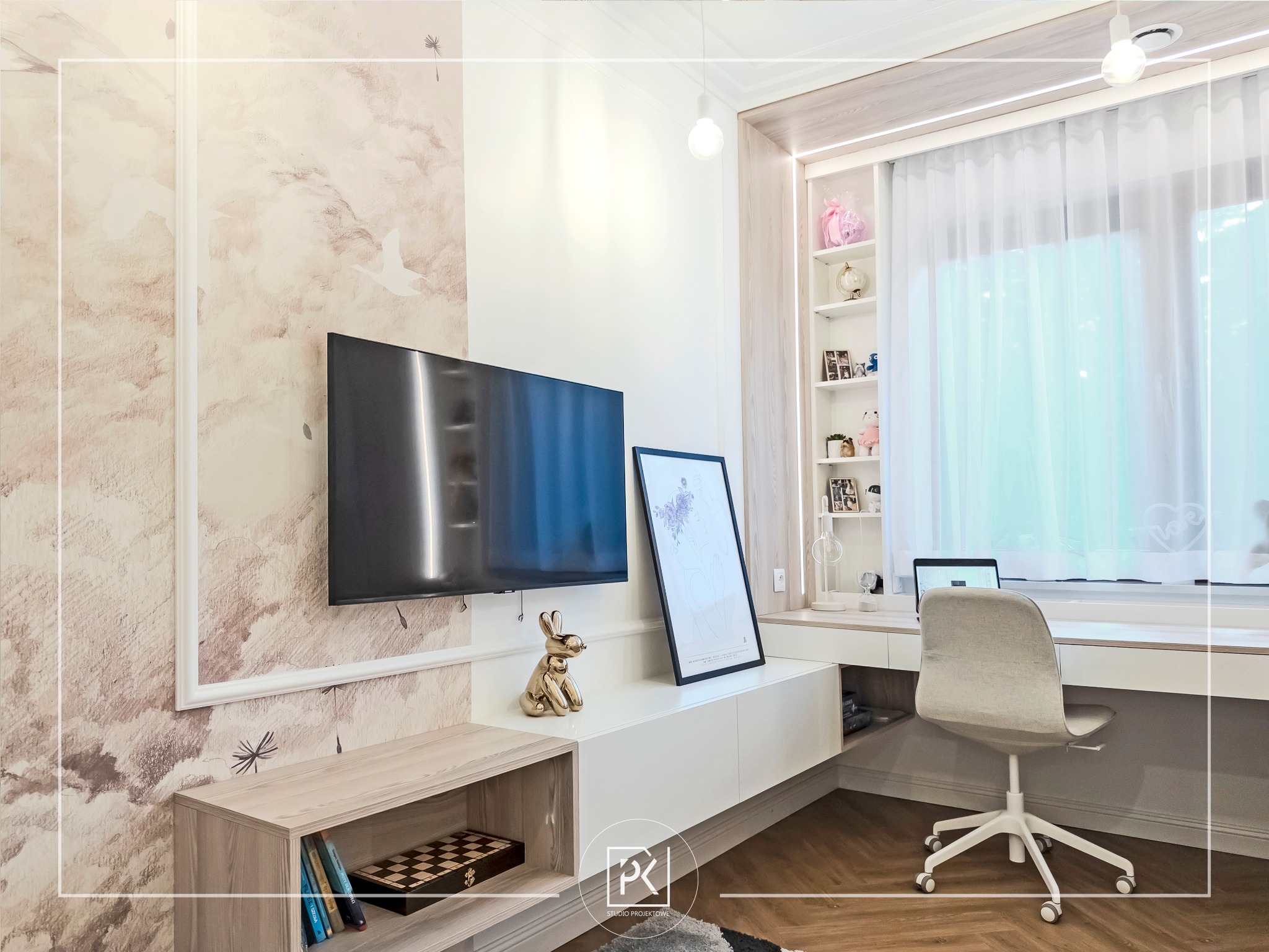 Nowoczesny pokój dzienny z miejscem do pracy: telewizor na ścianie z tapetą w pastelowe wzory, biurko z laptopem przy oknie z białymi zasłonami, złota figurka królika, drewniany parkiet w jodełkę.