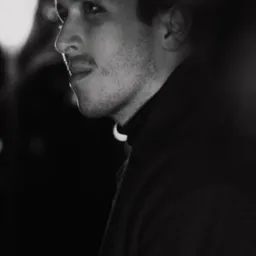 Czarno-białe portretowe ujęcie z profilu młodego mężczyzny w czarnym golfie, oświetlonego bocznym światłem, z widocznym fragmentem lampy w tle.