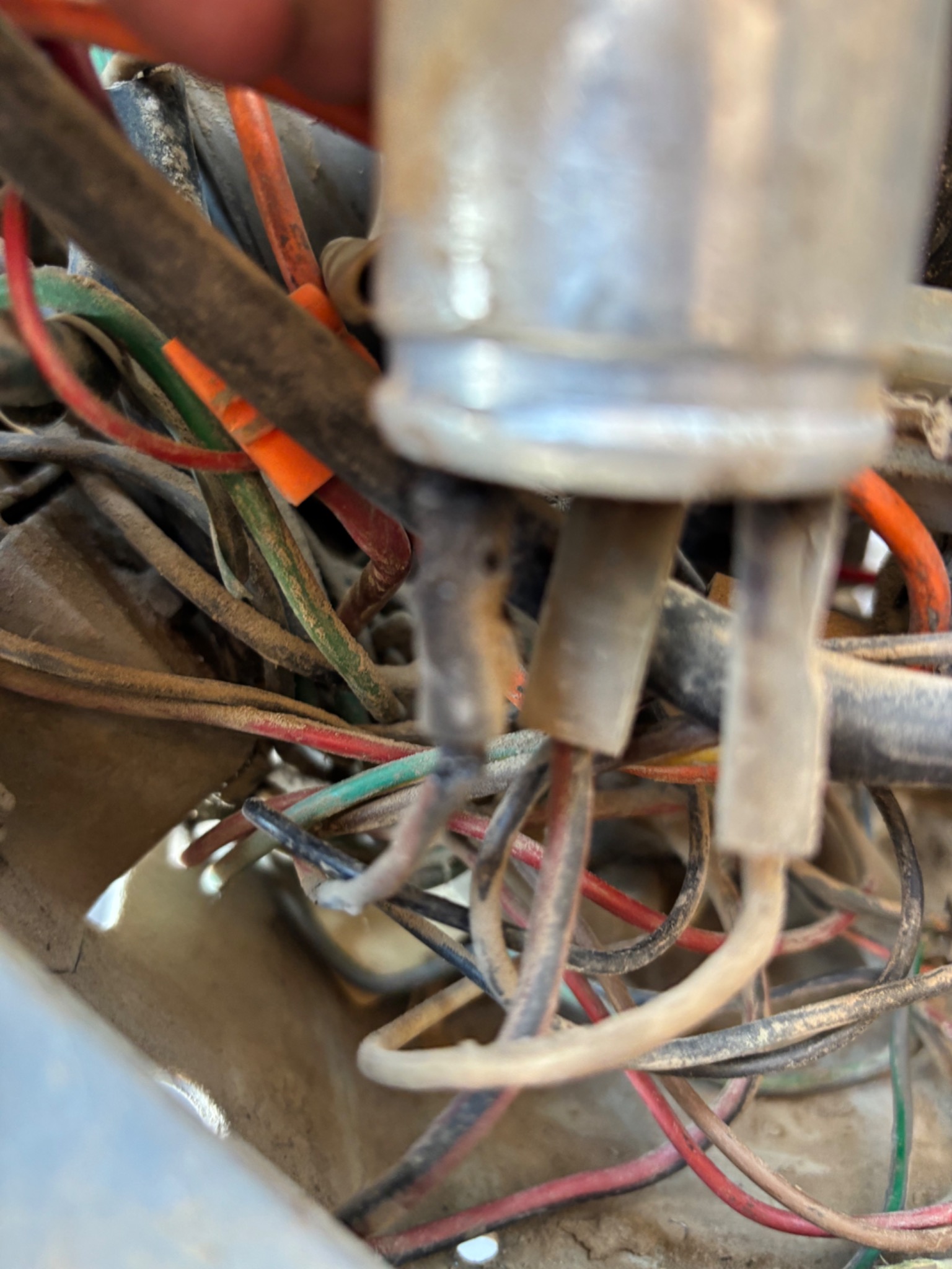 Zbliżenie na wiązkę przewodów elektrycznych w samochodzie, z widocznymi złączkami i różnymi kolorami izolacji, całość pokryta warstwą kurzu.