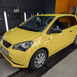 Wypolerowani Ernest Milewski - Żółty samochód Seat Mii po przyciemnianiu szyb, widoczne ciemne szyby, czarne felgi i reflektor. Samochód stoi na metalowej kracie w warsztacie.