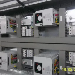 Rozdzielnica elektryczna z zamontowanymi falownikami LS i zabezpieczeniami, widoczne okablowanie i oznaczenia.