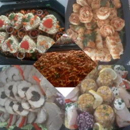 Cztery czarne tace z różnorodnymi przekąskami: sałatka jarzynowa z papryką w kształcie serca, roladki z ciasta francuskiego z ziołami, mięso pieczone ze śliwką i galaretki z kurczakiem i kukurydzą,...