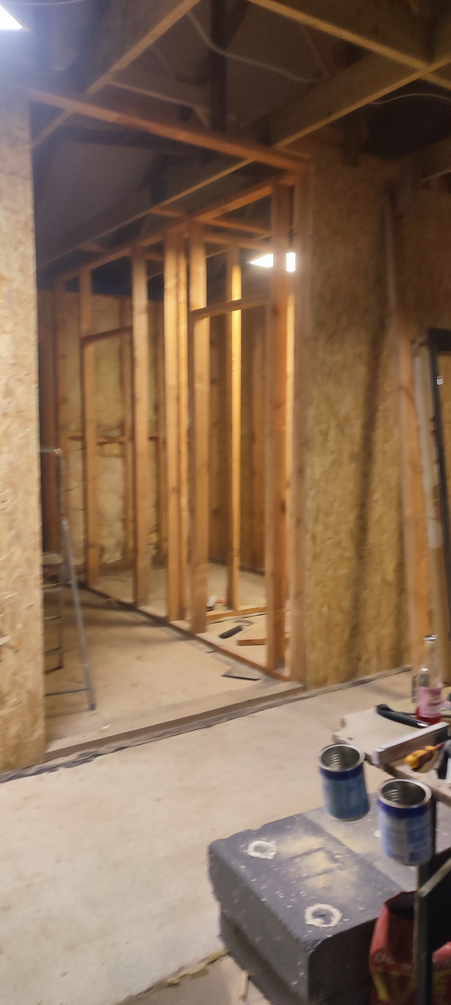 Konstrukcja ścian szkieletowych wewnątrz budynku w Świebodzinie, widoczne drewniane ramy i płyty OSB. Etap budowy z narzędziami w tle.