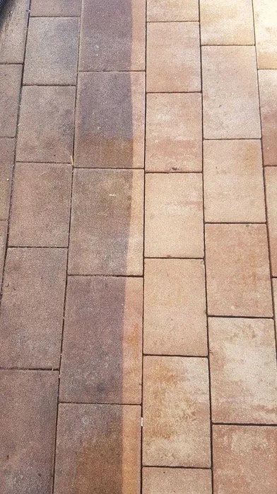 Częściowo wyczyszczona, brązowa kostka brukowa, ukazująca różnicę w kolorze i czystości przed i po zabiegu.