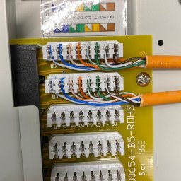 ElektroSync - Radosław Niżyński - Panel krosowniczy z podłączonymi kablami sieciowymi, widoczne oznaczenia kolorystyczne i numeryczne, detale złączy i przewodów. Precyzyjne połączenia.