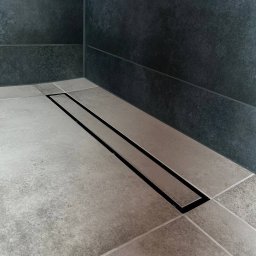 ReNovoPro Oleksandr Shevchenko - Nowoczesny odpływ liniowy z czarną ramką w jasnoszarej, kwadratowej posadzce łazienki, ciemne płytki na ścianie w tle.