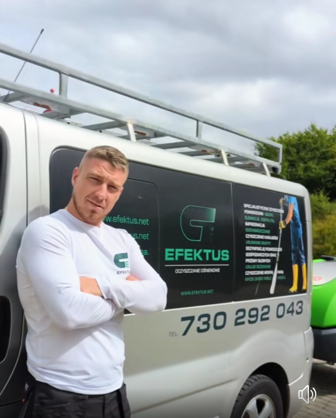 Mężczyzna w białej koszulce z długim rękawem stoi z założonymi rękami obok srebrnego samochodu dostawczego z logo i danymi kontaktowymi firmy 'Efektus' oferującej specjalistyczne czyszczenie...