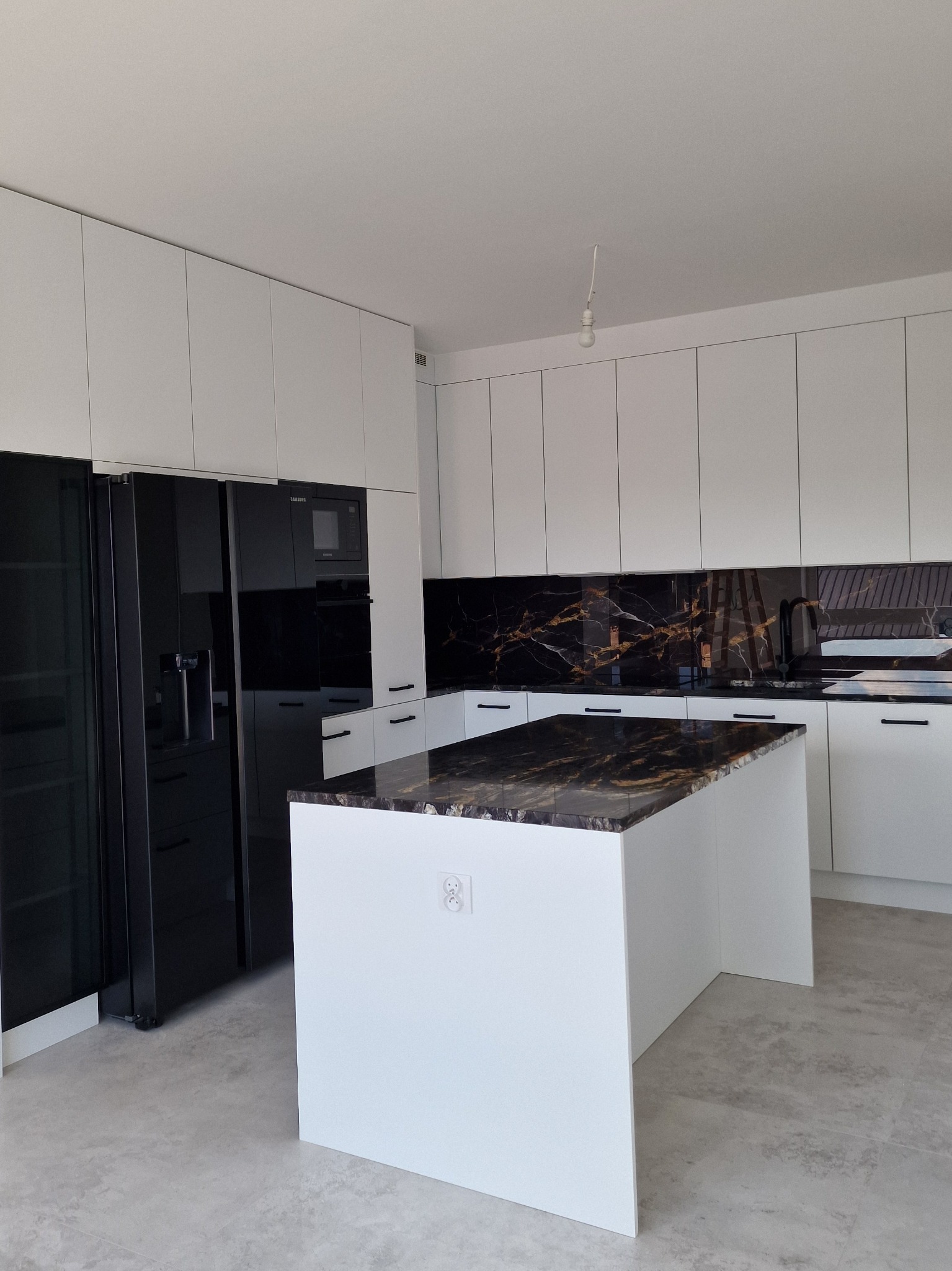 Kuchnia z frontami akrylowymi biały mat z blatem granitowym i grafiką na szkle między meblami