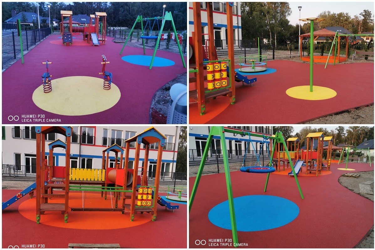 Nowoczesny, kolorowy plac zabaw z bezpieczną, czerwoną nawierzchnią w Mysłowicach, z huśtawkami, zjeżdżalniami i urządzeniami do wspinaczki, otoczony budynkiem i zielenią.