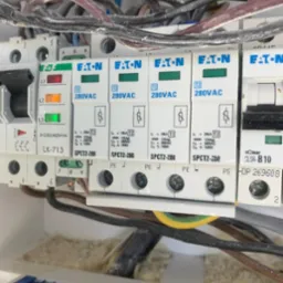 Rozdzielnica elektryczna z zabezpieczeniami przeciwprzepięciowymi marki Eaton SPCT2-280, widoczne przewody i listwa zaciskowa z niebieską obudową.