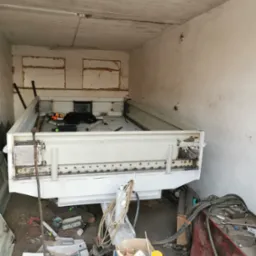 Spawanie przyczepy w warsztacie w Chojnicach. Widoczne ślady spawania i świeża farba. Przyczepa w trakcie renowacji, narzędzia i materiały w tle.