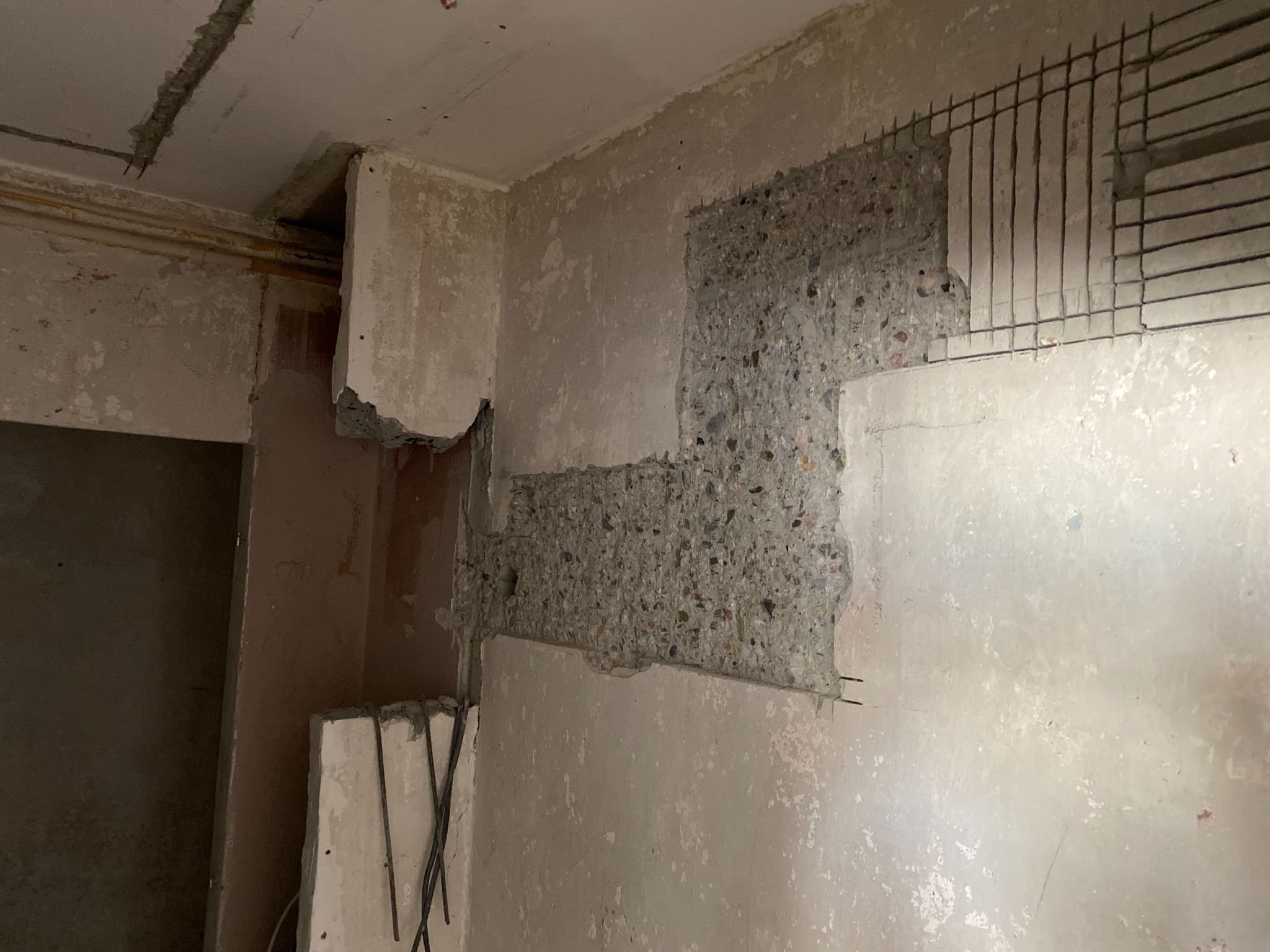 Przygotowanie pod instalację elektryczną w ścianie z wyciętymi bruzdami i wystającymi przewodami. Widoczne surowe wykończenie ścian.