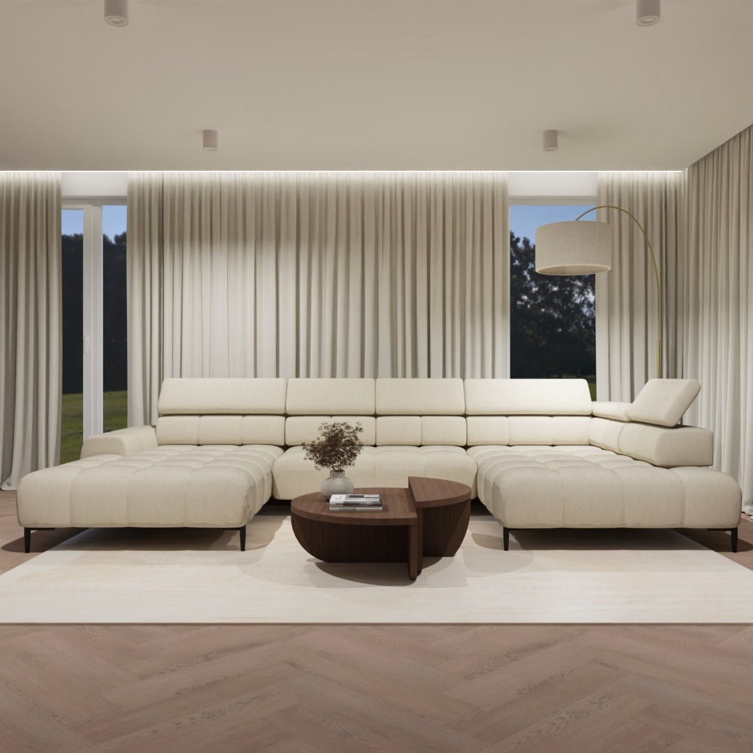 Jasny, modułowy narożnik z pikowanymi siedziskami w przestronnym salonie z parkietem w jodełkę i kremowymi zasłonami, okrągły stolik kawowy z dekoracją kwiatową.