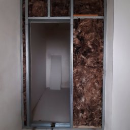 ALLES - Wnętrze ściany z widoczną izolacją z wełny mineralnej i metalową konstrukcją nośną, przygotowane do dalszych prac wykończeniowych.