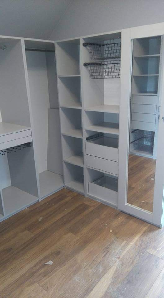 Jasnoszara szafa wnękowa z koszami i lustrzanymi drzwiami przesuwnymi, widok z dołu, drewniana podłoga, skośny sufit.
