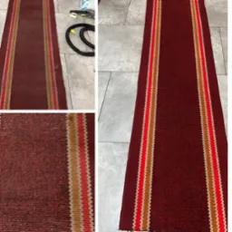 Widok z góry na czerwony dywanik z paskami w kolorach czerwonym i beżowym, po lewej stronie widoczne zabrudzenia przed czyszczeniem, po prawej dywanik po czyszczeniu, w tle sprzęt do czyszczenia...
