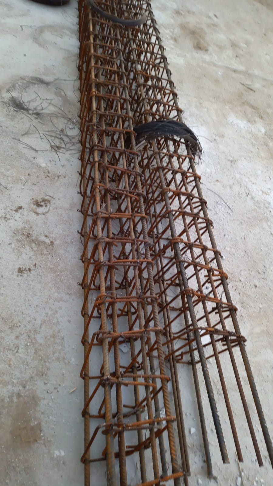 Gotowe szkielety zbrojeniowe, połączone drutem wiązałkowym, przygotowane do zalania betonem na fundamencie.