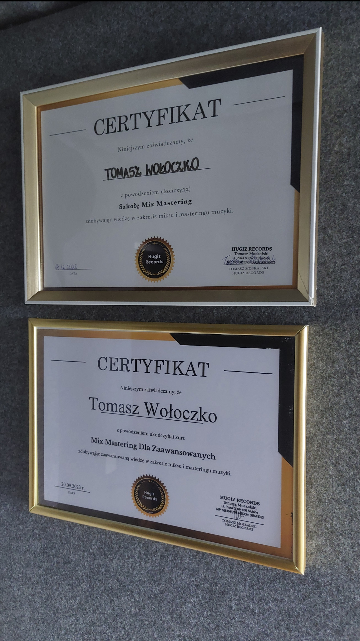 Dwa oprawione certyfikaty ukończenia kursów miksu i masteringu muzyki, wydane przez Hugiz Records, z datami 15.12.2020 oraz 20.09.2023, widoczne logo firmy.