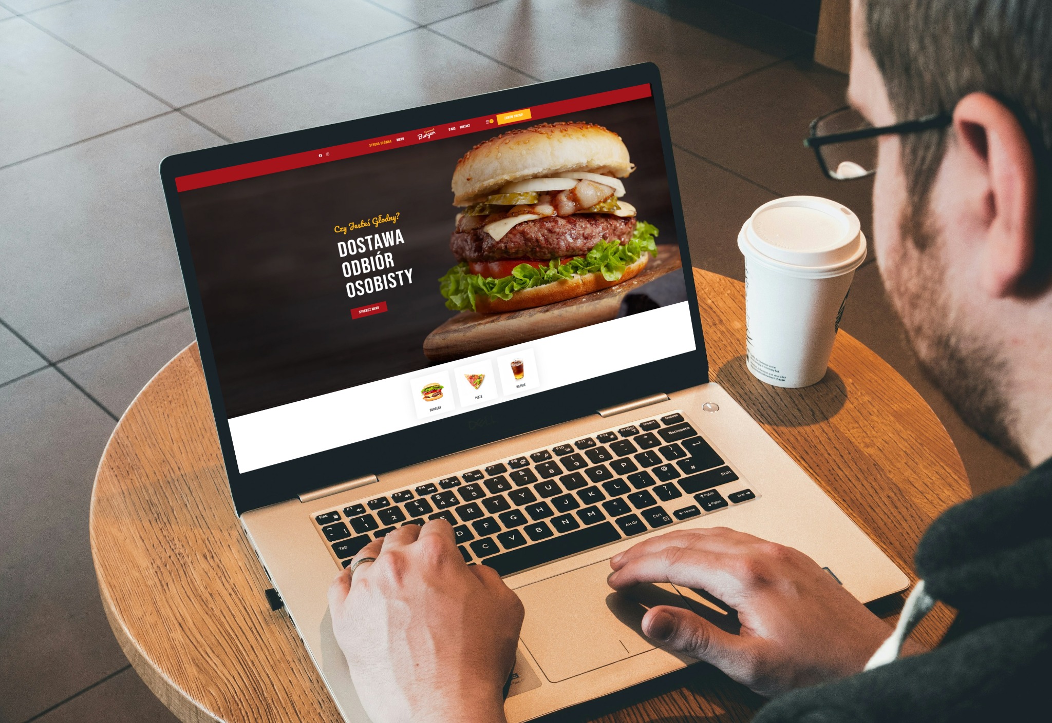 Mężczyzna używa laptopa z szablonem strony fast food (burgery, pizza, napoje) z opcją zamówień online i kodem QR na stoliku. Widoczny kubek z kawą.