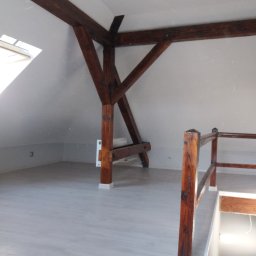 Łukasz Gajdamowicz - Poddasze z drewnianą konstrukcją nośną i oknem dachowym, wykończone panelami podłogowymi i pomalowane na szaro.